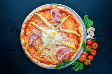 Pizza with asparagus and bacon. On a wooden background. Top view. Free space for your text.
