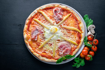 Pizza with asparagus and bacon. On a wooden background. Top view. Free space for your text.