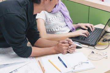 An Asian male supervisor is teaching a female staff at an office desk at office in selective focus.