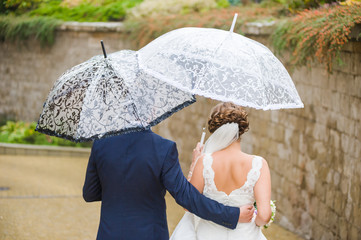 Rainy wedding day. Groom with bride under umbrella