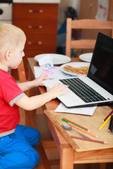 Fototapeta na wymiar Little boy using laptop computer playing games
