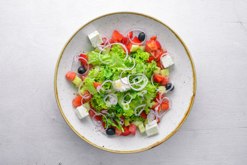 Greek salad of fresh vegetables and cheese. On a wooden background. Top view. Free space for your text.