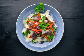 Veal and fresh vegetables salad. On a wooden background. Top view. Free space for your text.