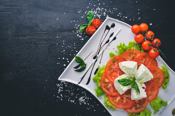 Mozzarella cheese with tomatoes and olive oil. Italian food. On a wooden background. Top view. Free space for text.