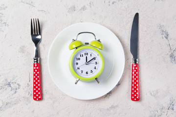 Alarm clock with bells on the plate with fork and knife, lunch time concept, top view with copy...