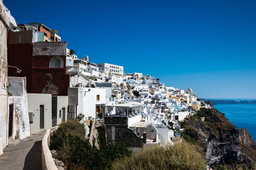 Naklejka premium Fira, Thira town, Santorini Cyclade islands, Greece. Beautiful view of the town with white buildings, blue church's roofs and many colored flowers.