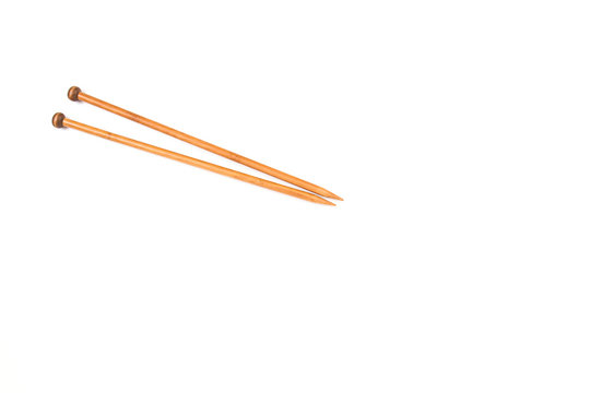 A pair of wooden knitting needles on white background.