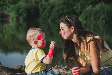 Mother with the child play paints. The child plays paints on the sands.