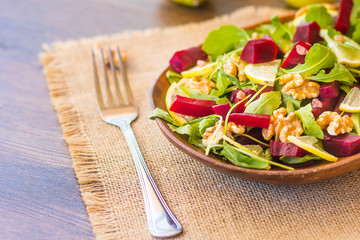 Salad with arugula, beets and nuts In a glass jar in a wooden plate