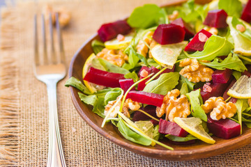 Salad with arugula, beets and nuts In a glass jar in a wooden plate
