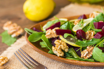 Salad with arugula, beets and nuts In a glass jar in a wooden plate