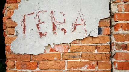 Brickwork with crumbled plaster. The writing is on the wall