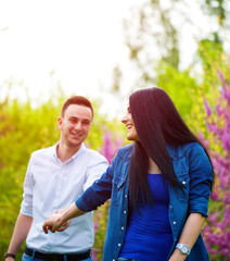 Obraz premium young woman holding man's hand and leading him on nature outdoor