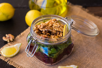 Salad with arugula, beets and nuts In a glass jar in a wooden plate