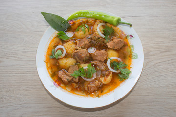 Beef stew served with cooked potatoes in a ceramic plate on a wooden background