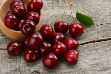 cherries in bowl on old wooden background. Top view with copy space.