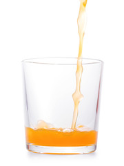 Orange drink pouring in clear glass. Isolated with clipping path