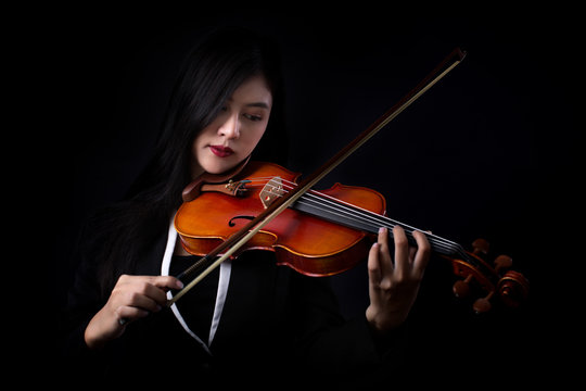 Playing the violin. Musical instrument with hands on dark background.