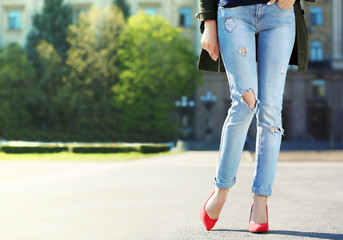 Young woman with slim legs in high heels and jeans on street