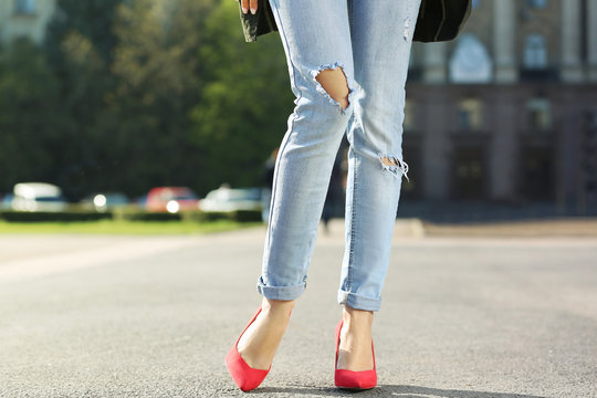 Young woman with slim legs in high heels and jeans on street