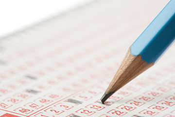 Close-up of a lottery ticket and pencil isolated on white background.   