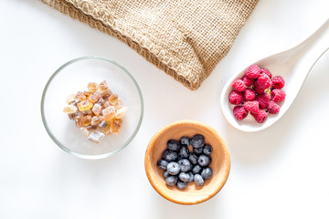 Making summer preserve. Raspberry, blueberry and sugar on white background top view