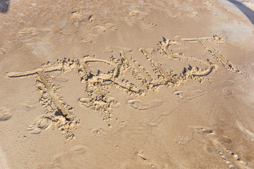 Trust written in the sand on a sunset beach