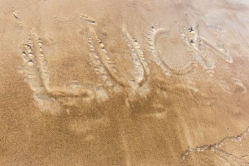Luck written in the sand on a sunset beach