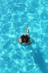 Young girl swimming underwater in the clear water of the pool