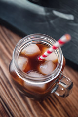 Mason jar with cold brew coffee and straw on wooden table