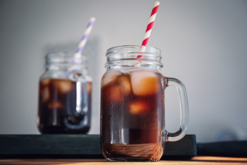 Mason jar with cold brew coffee and straw on wooden table