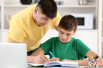 Father and son doing homework together indoors