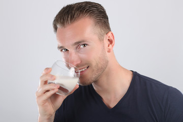 Bel homme européen buvant un verre de lait sur un fond blanc 