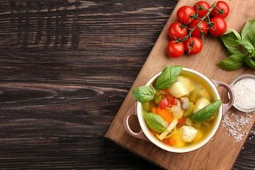 Composition with homemade turkey soup in casserole on wooden table