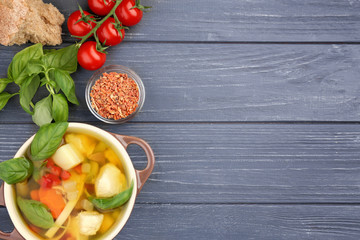 Composition with homemade turkey soup in casserole on wooden table
