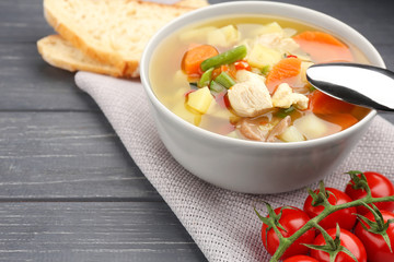 Composition with homemade turkey soup in bowl on wooden table