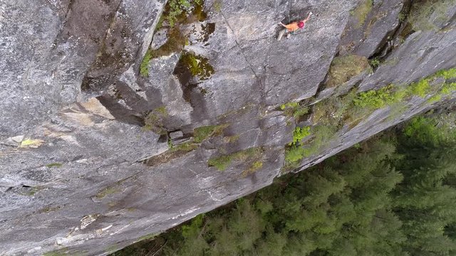 Aerial of Rock Climber High on Rocky Cliff Scouting Route Up Pacific Northwest Mountain