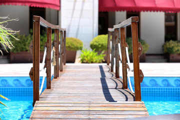 Wooden bridge over swimming pool in luxury hotel
