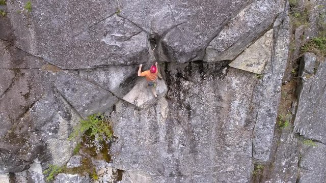 Aerial of Professional Rock Climber on Dangerous Mountain Cliff High Above Forest Canopy