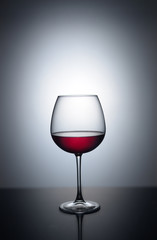 Splash of red wine in a glass on a white background with reflection