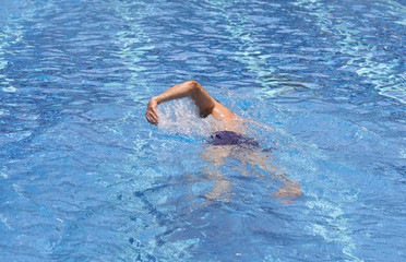 Strong muscular man swimming in pool crawl style. Active summer holiday vacation. Sport, healthy lifestyle concept