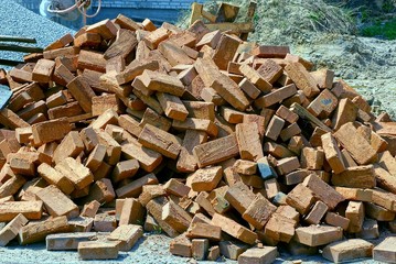 Куча коричневых кирпичей лежат на улице на стройплощадке