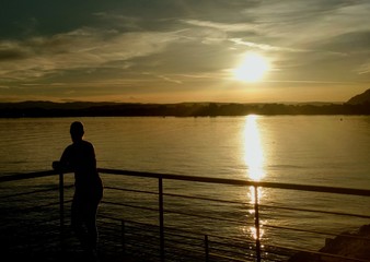 Naklejka na ściany i meble fille qui regarde un coucher de soleil sur le lac d'Annecy