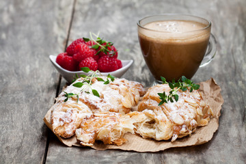 homemade  fresh almond croissant with cup of cappuccino on rustic wooden table