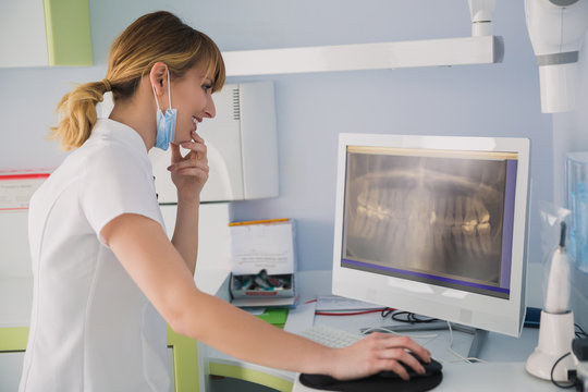 Young female dentist examining patient teeth X Ray