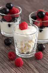 Fresh cheese with raspberries and currants. Yogurt with fresh berries. Brown wooden table