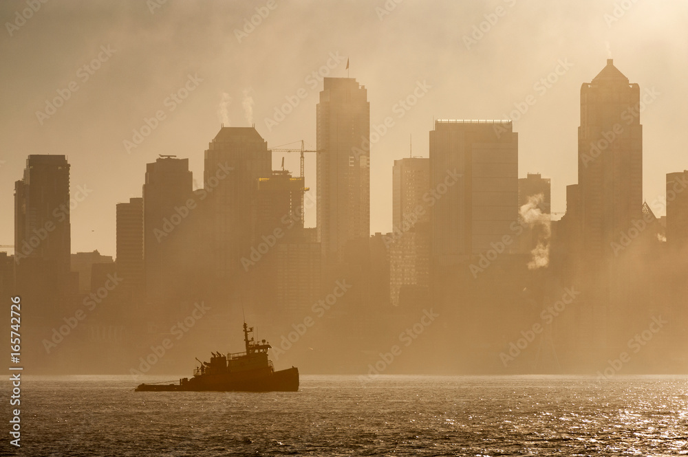 Wall mural Tug Boat on Elliott Bay on a Foggy Morning. The Seattle skyline is silhouetted as a tugboat works the waters of Elliott Bay during a glorious foggy sunrise.