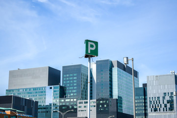 The tall business skyscrapers and the parking sign in the heart of Montreal downtown