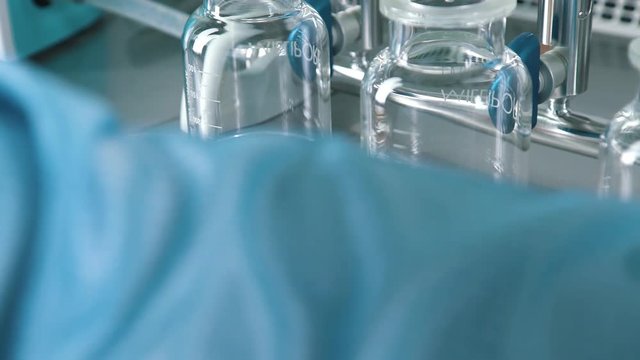 Laboratory equipment and lab assistant's work: hands of the scientist in sterile blue gloves are prepared by catalysts and test systems. Work with reagents and reagents.