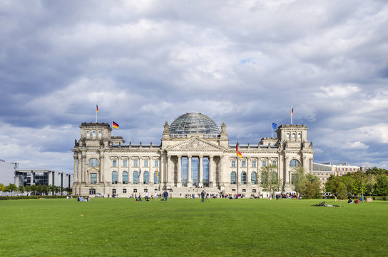 Reichstag building, German Parliament, and people enjoying a summer holiday on the lawn. The dedication Dem deutschen Volke, To the German people, on the frieze